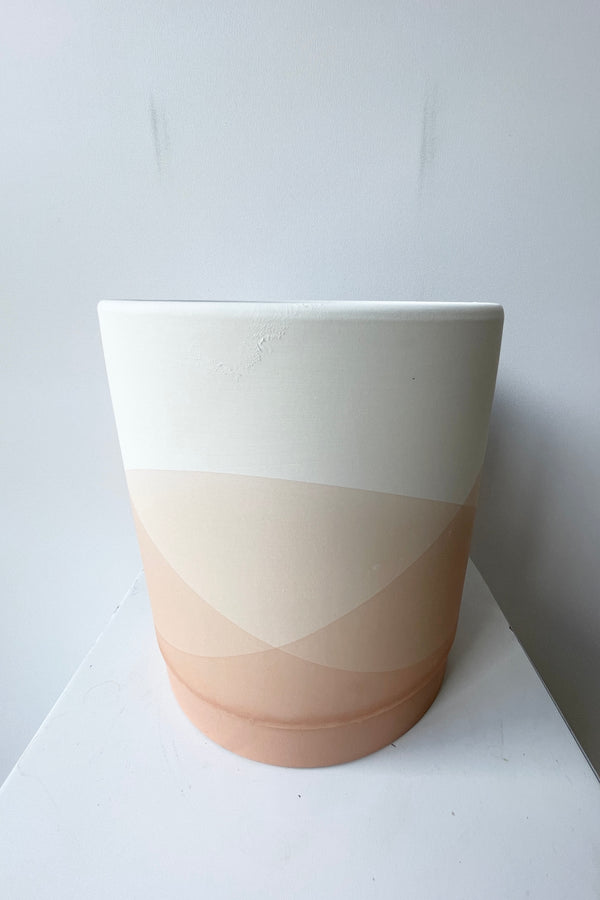 The large Vesper Pot and saucer shown from the side at eye level with its striations of pink and beige. 