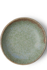 Terra Green saucer dish shown from the top against a white wall. 