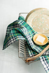 The Helen Kitchen Cloth from Fog Linen Work in a dish rack dryer with a dish and a bowl of soap.