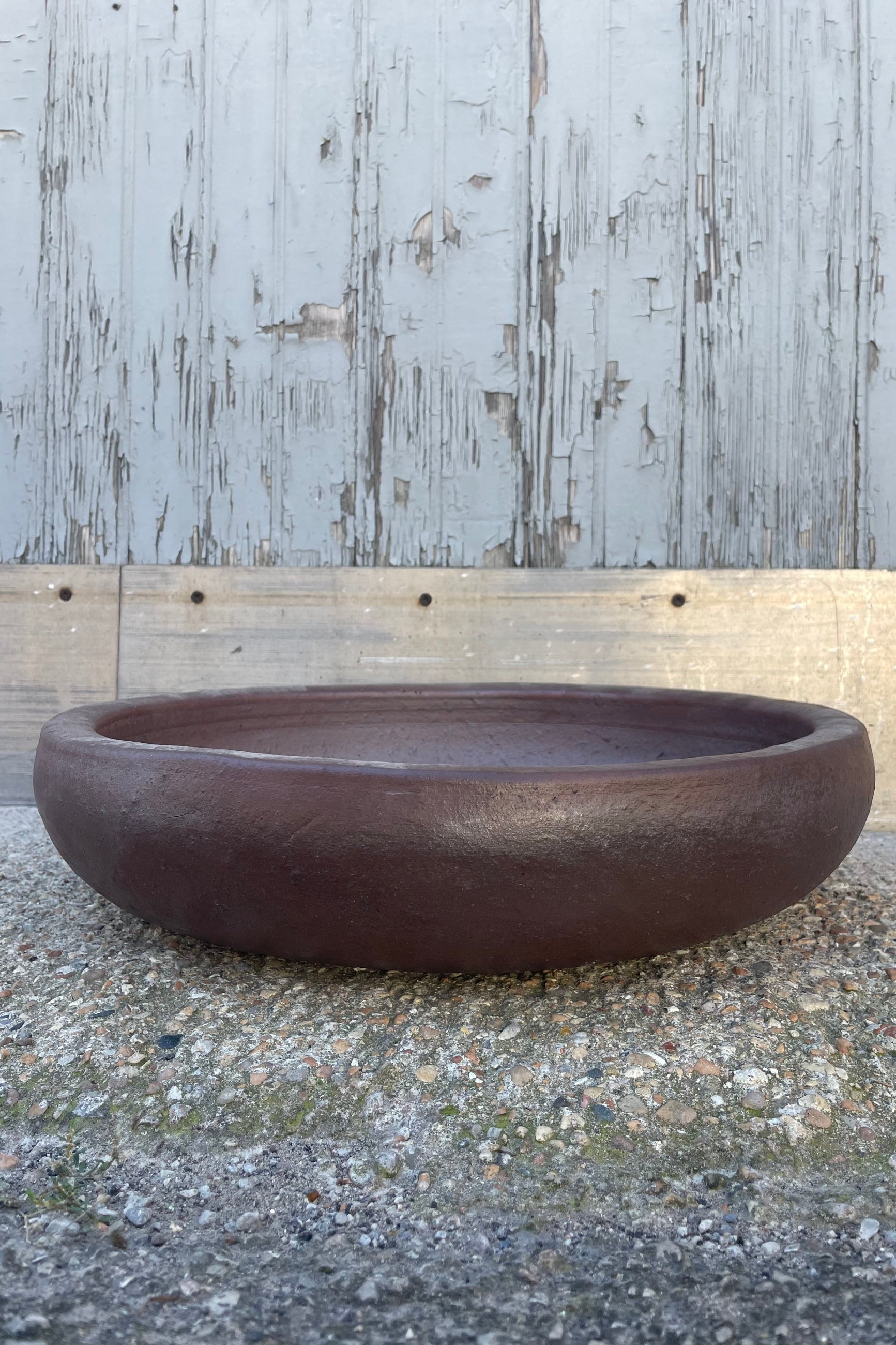 A low bowl with brown glaze in front of a wooden wall ©Sprout Home