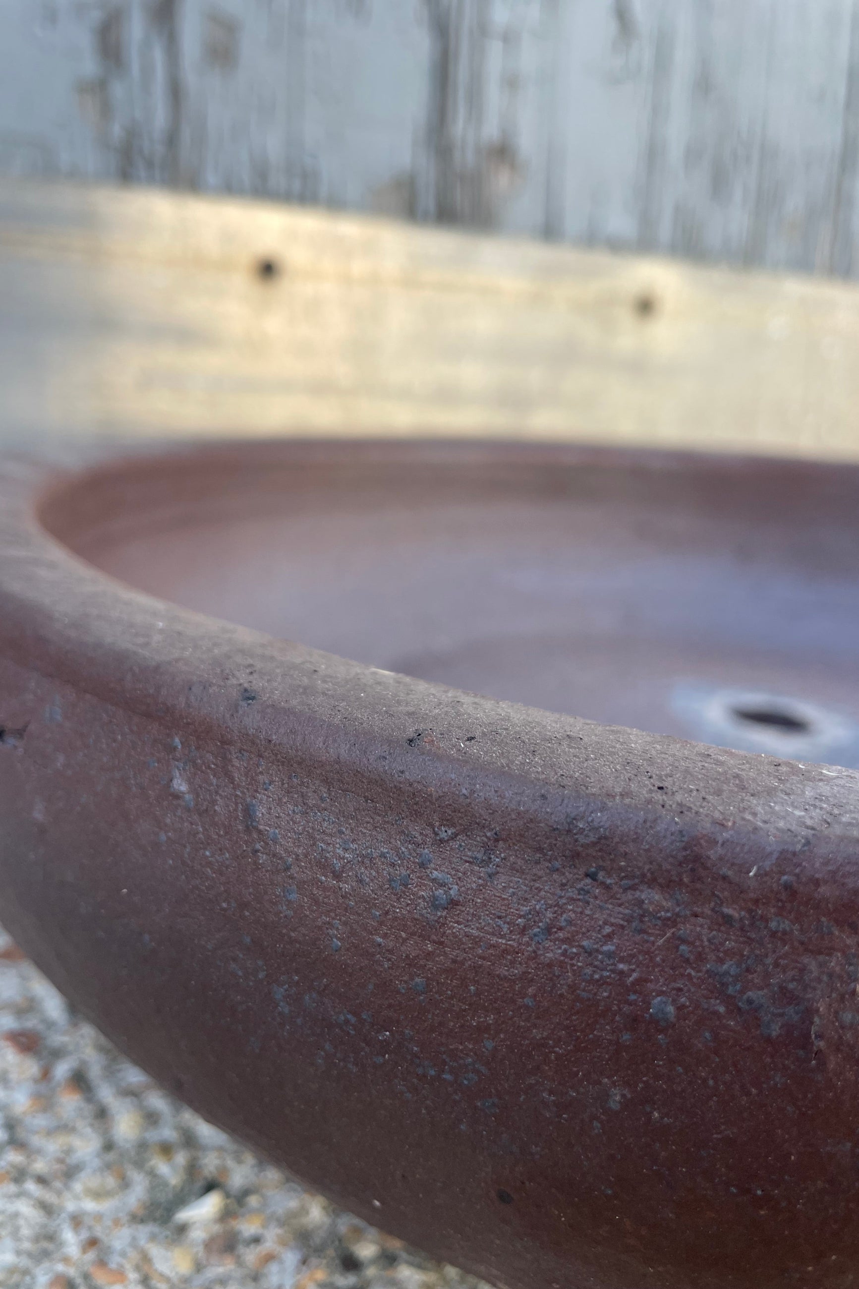 Close photo of A low bowl with brown glaze in front of a wooden wall ©Sprout Home