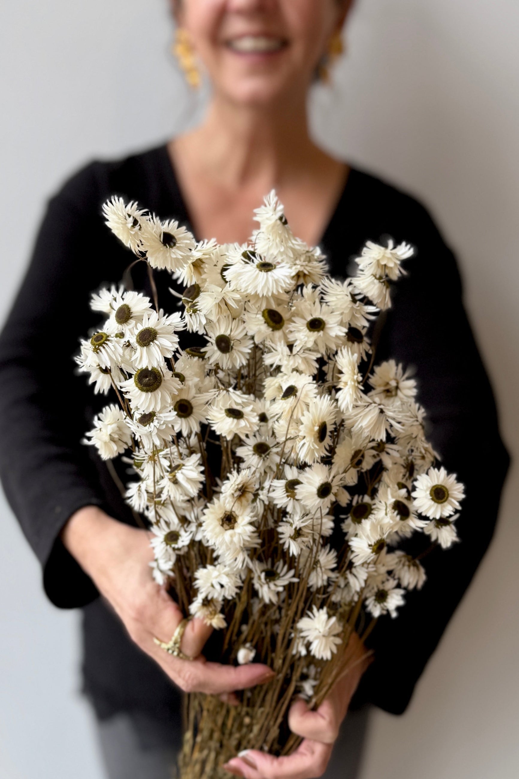 Person holding a bouquet of white flowers against a neutral background ©Sprout Home