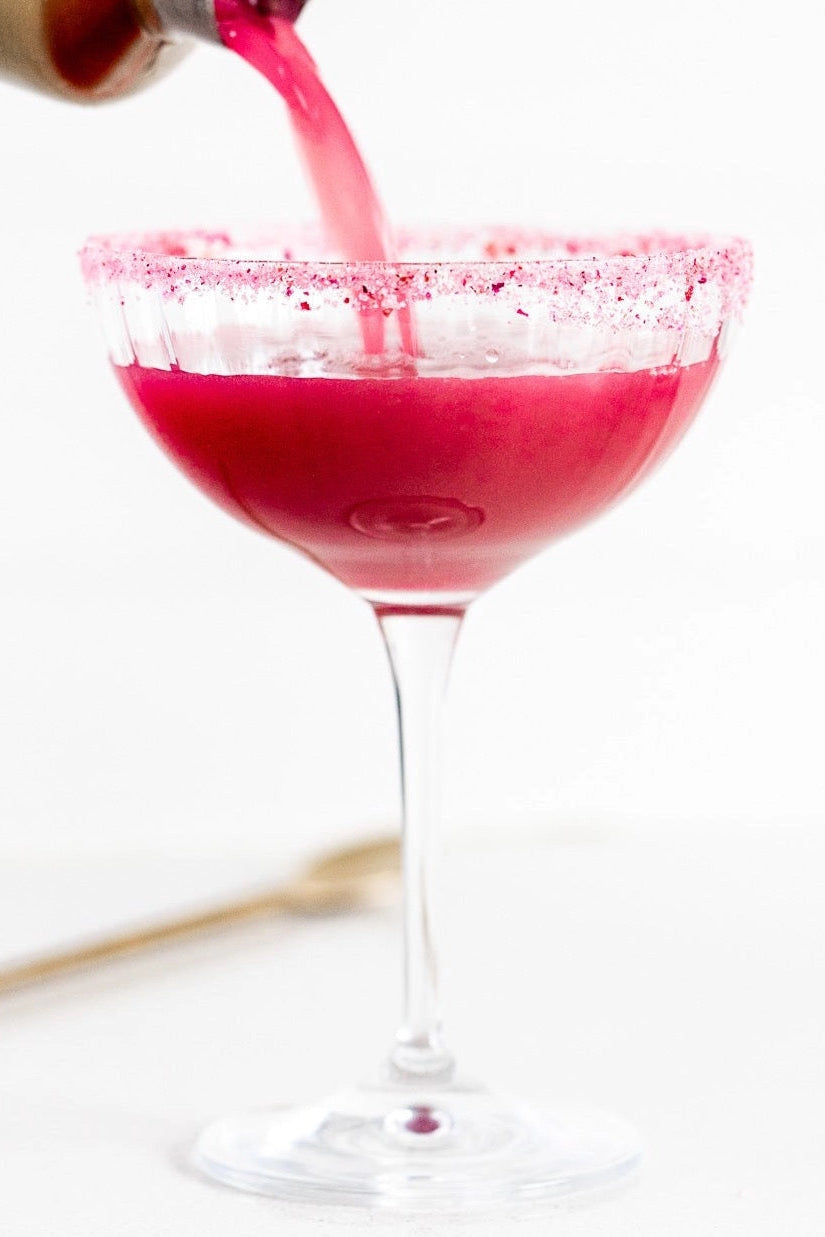 Pink cocktail being poured into a glass with a white background  ©Flouwer Co.