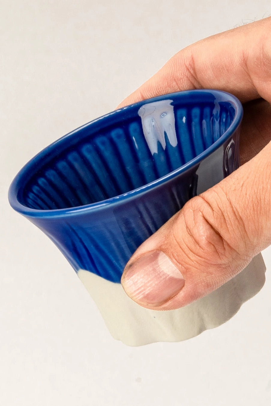 Hand holding a blue and white coffee pod against a light background  ©Urban Tokyo