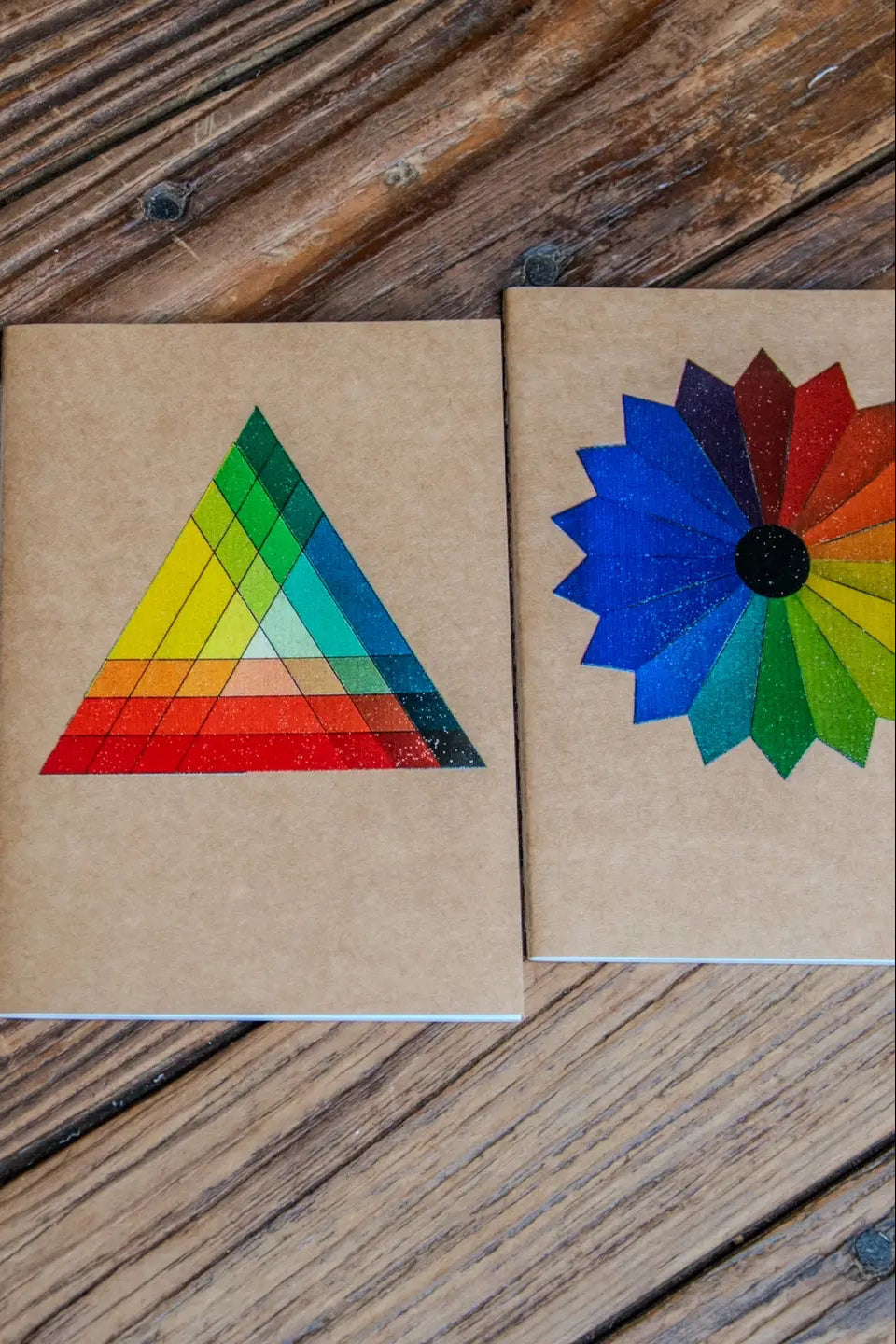 Color Theory Pack Travel Journal 3 Pack Notebooks with colorful geometric designs on a wooden surface ©Glum Lot Press