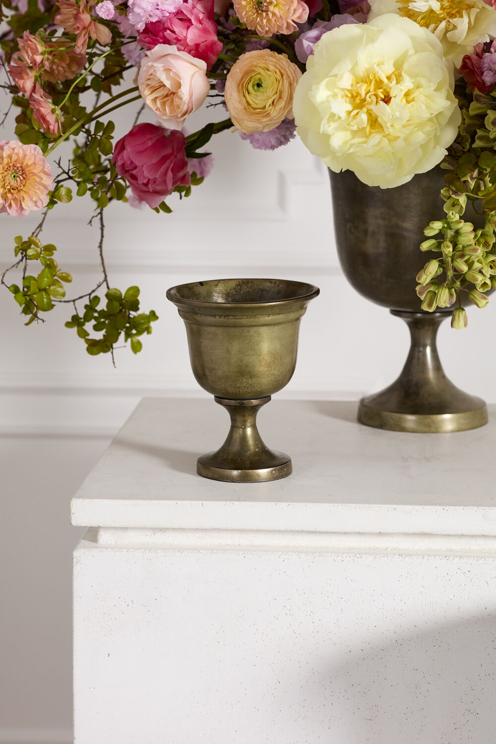 Two bronze Hullen vases on a white surface with flowers in the background ©Accent Decor