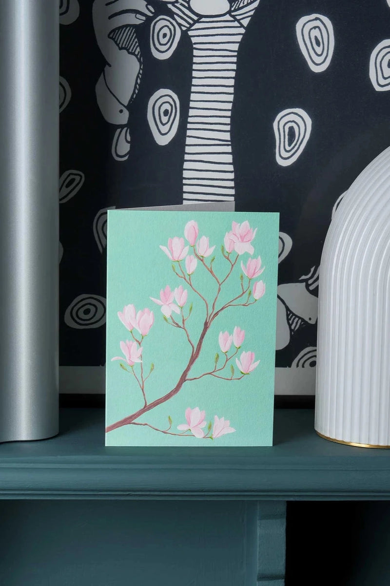 Magnolia Greeting card by Stengun Drawings on a teal shelf in a lifestyle shot.