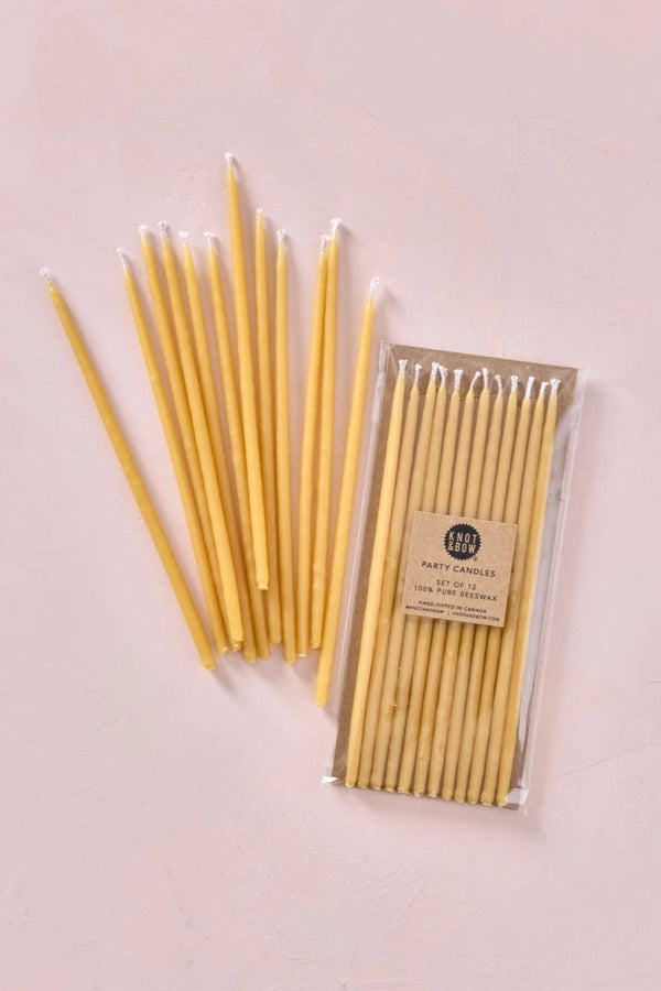 Knot & Bow Tall Natural beeswax candles in their packaging and a set out of their packaging.