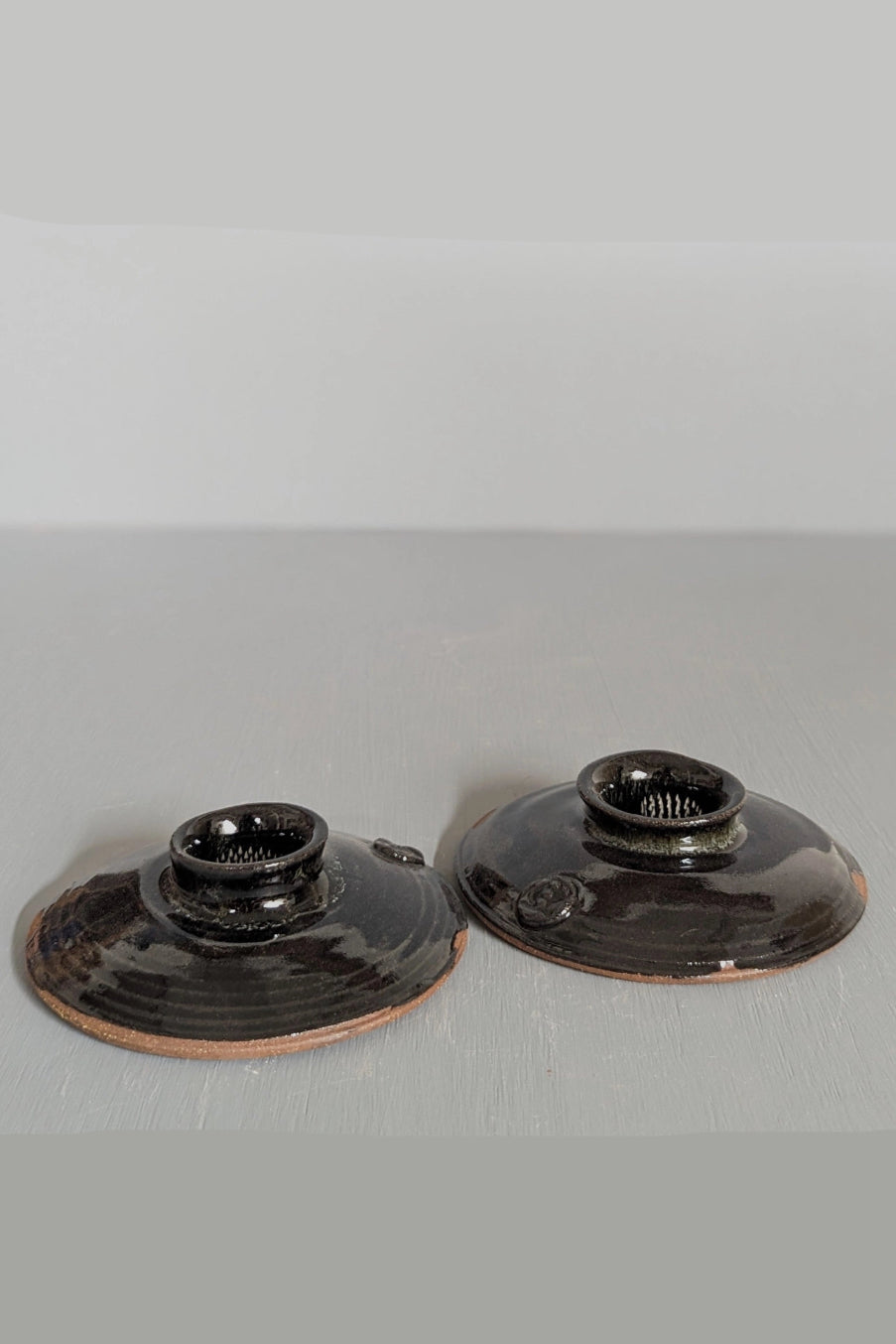 Two black ceramic ikebana bud vase on a gray surface with a white background ©South Creek Studios