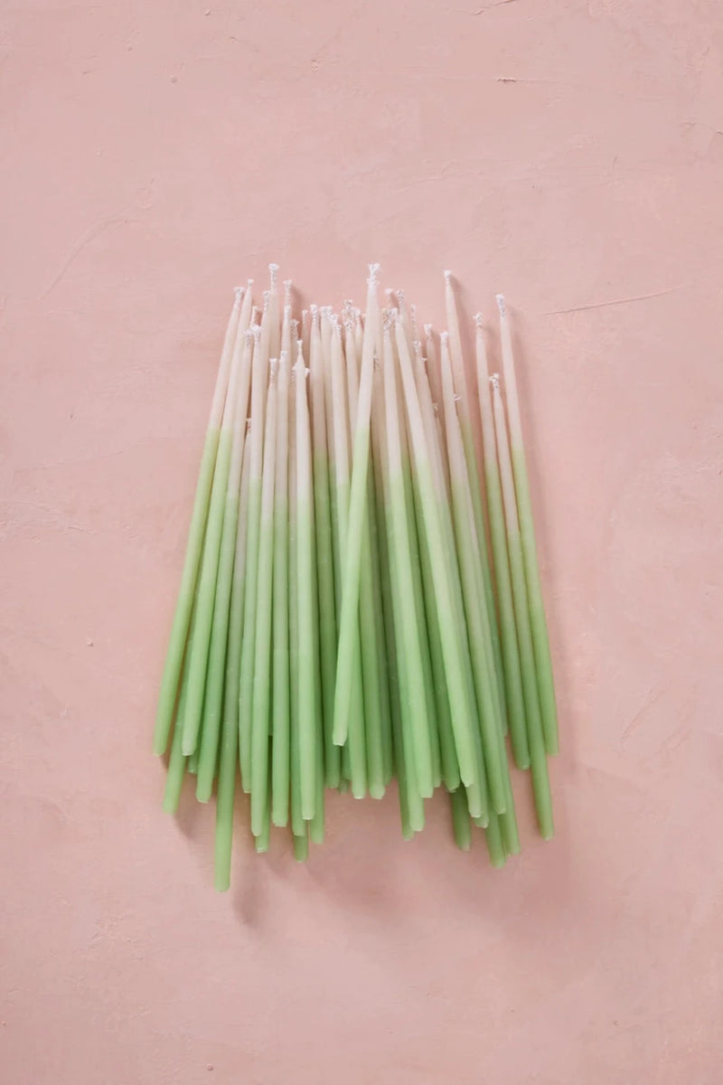 Knot & Bow tall Mint Ombre beeswax candles out of the packaging and laying on a pink background