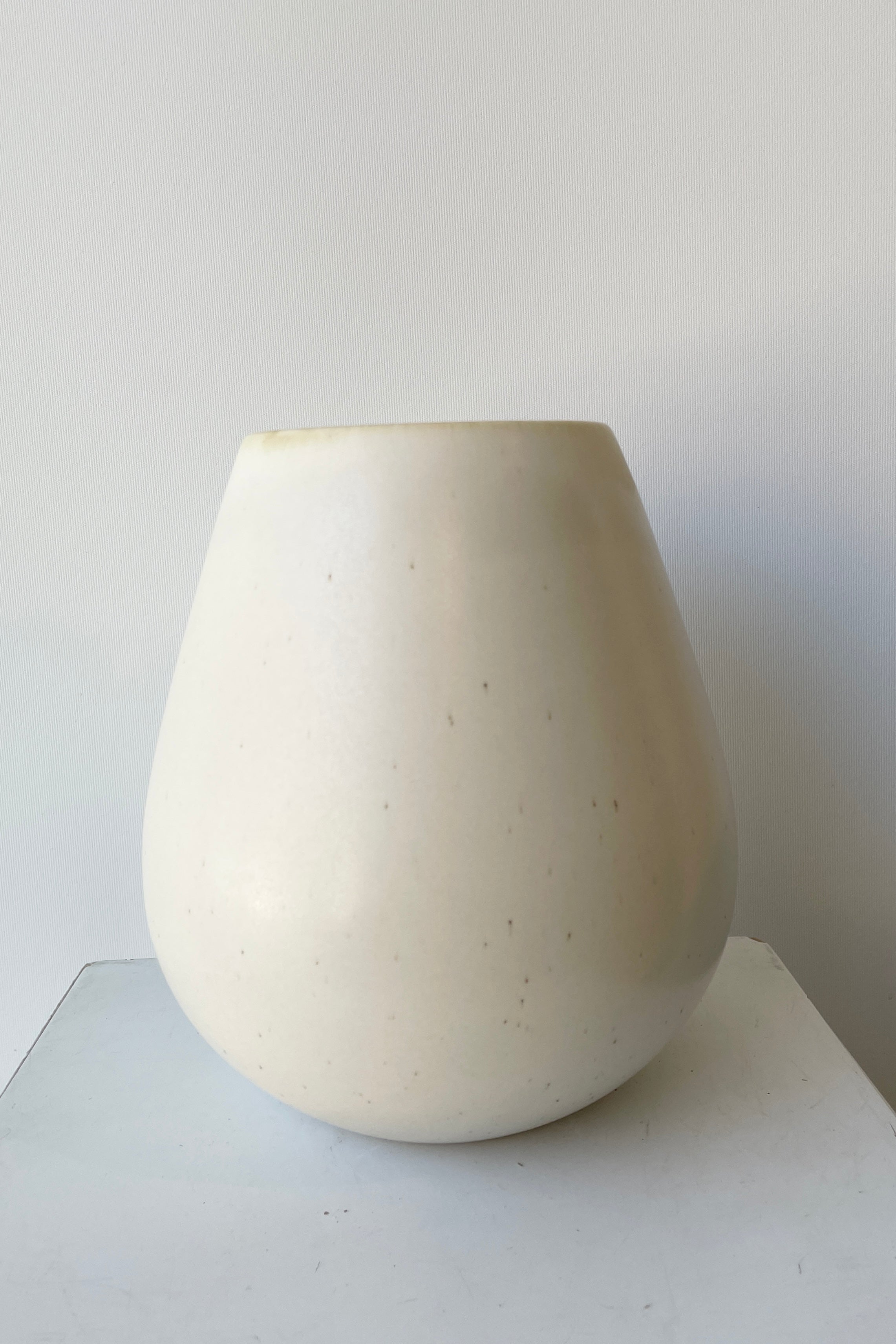 Ease vase in a Soft Shell color against a white wall