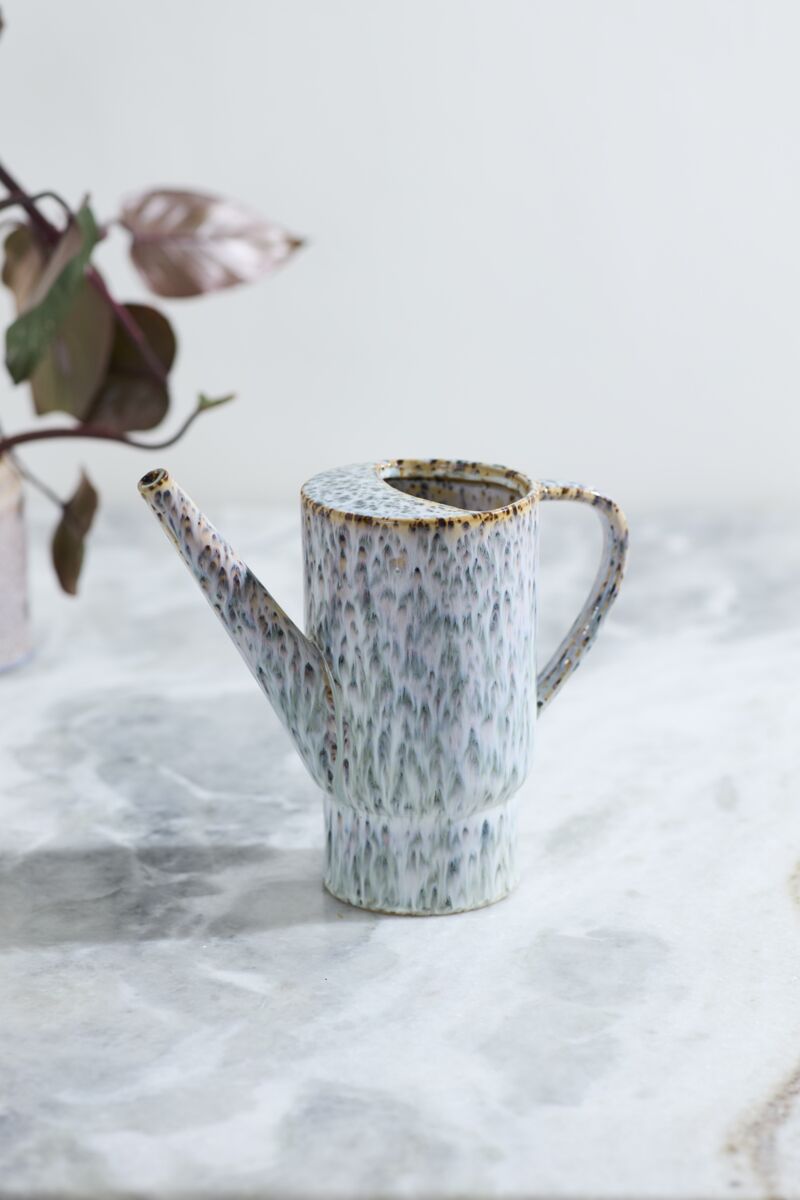 Speckled ceramic Lucien watering can on a marble surface with a blurred plant in the background ©Accent Decor
