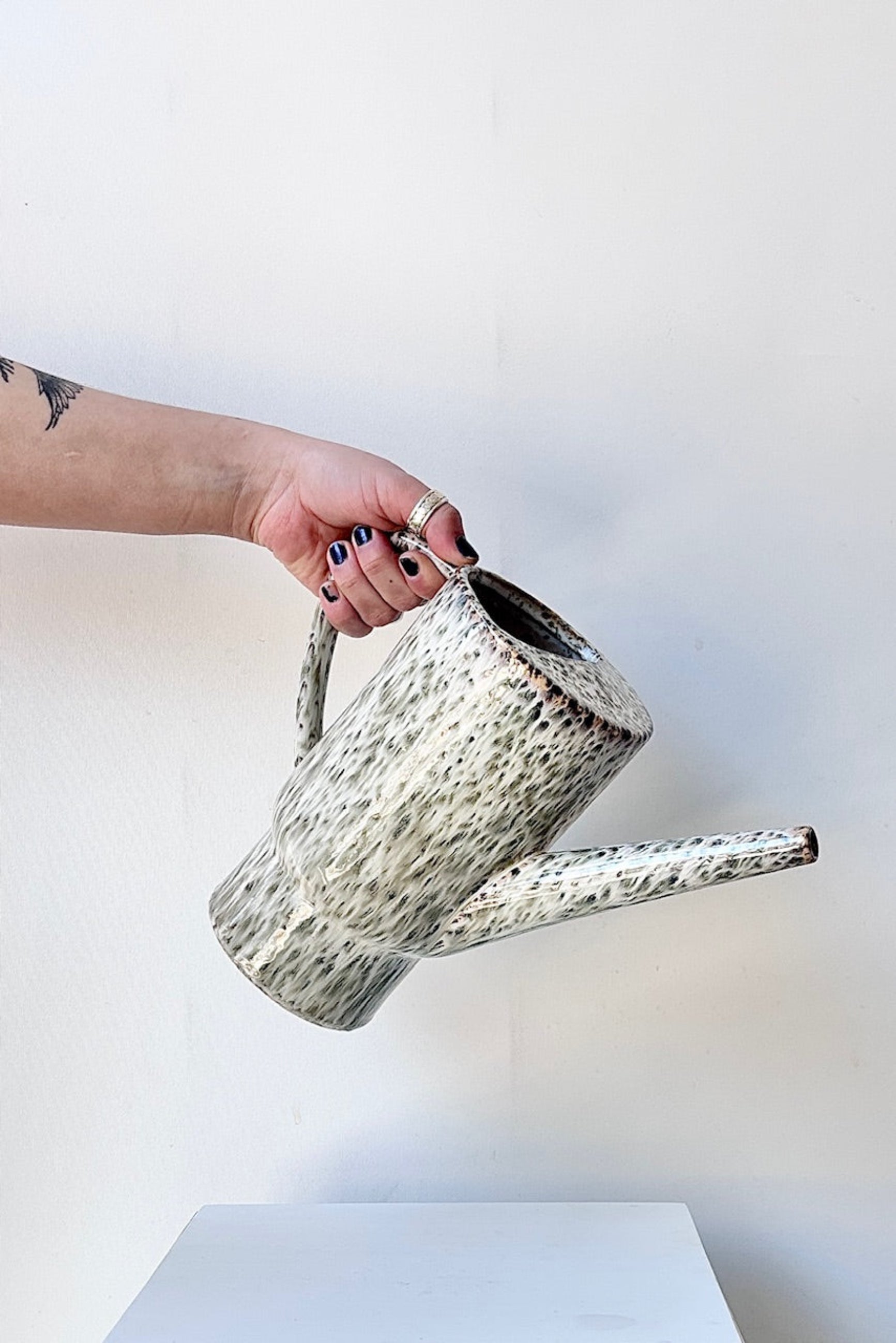 Hand holding ceramic Lucien pitcher with speckled pattern on a white background ©Sprout Home