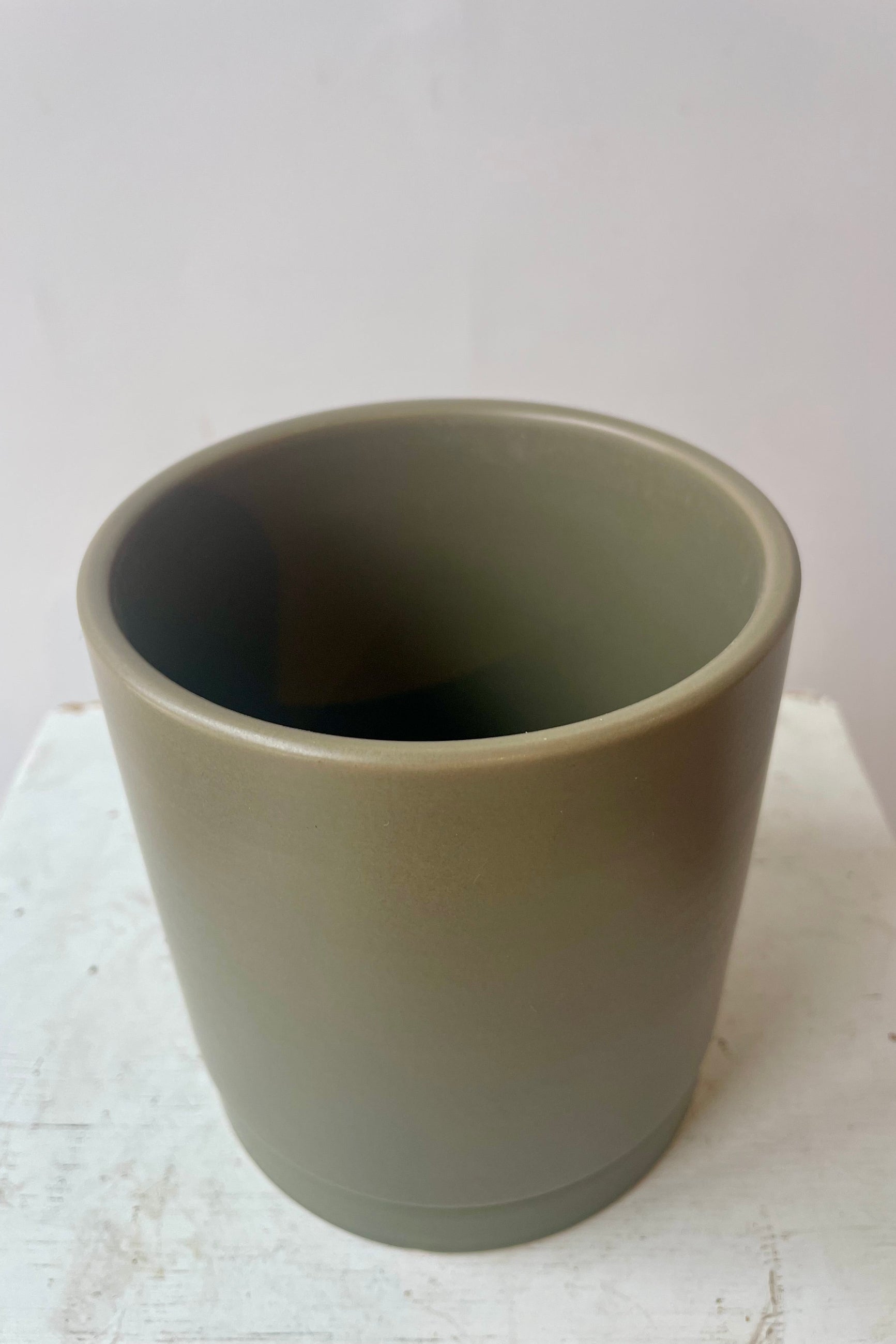 Photo of khaki colored cylindrical pot and saucer in front of a white wall ©Sprout Home