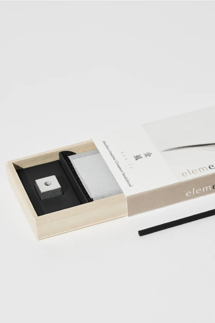 A white box of incense with a weight and incense stick in a white room ©Nippon Kodo