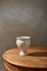 Magnolia vase on a wood table and a tan background.