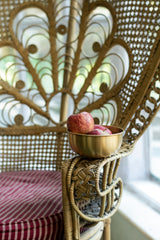 The Extra large brass bowl with apples and sitting on a wicker chair arm by Fog Linen Work.