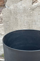 Photo of the top of a Black Metal Compote Pot against a cement wall