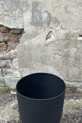 Photo of the top of a Black Metal Compote Pot against a cement wall.