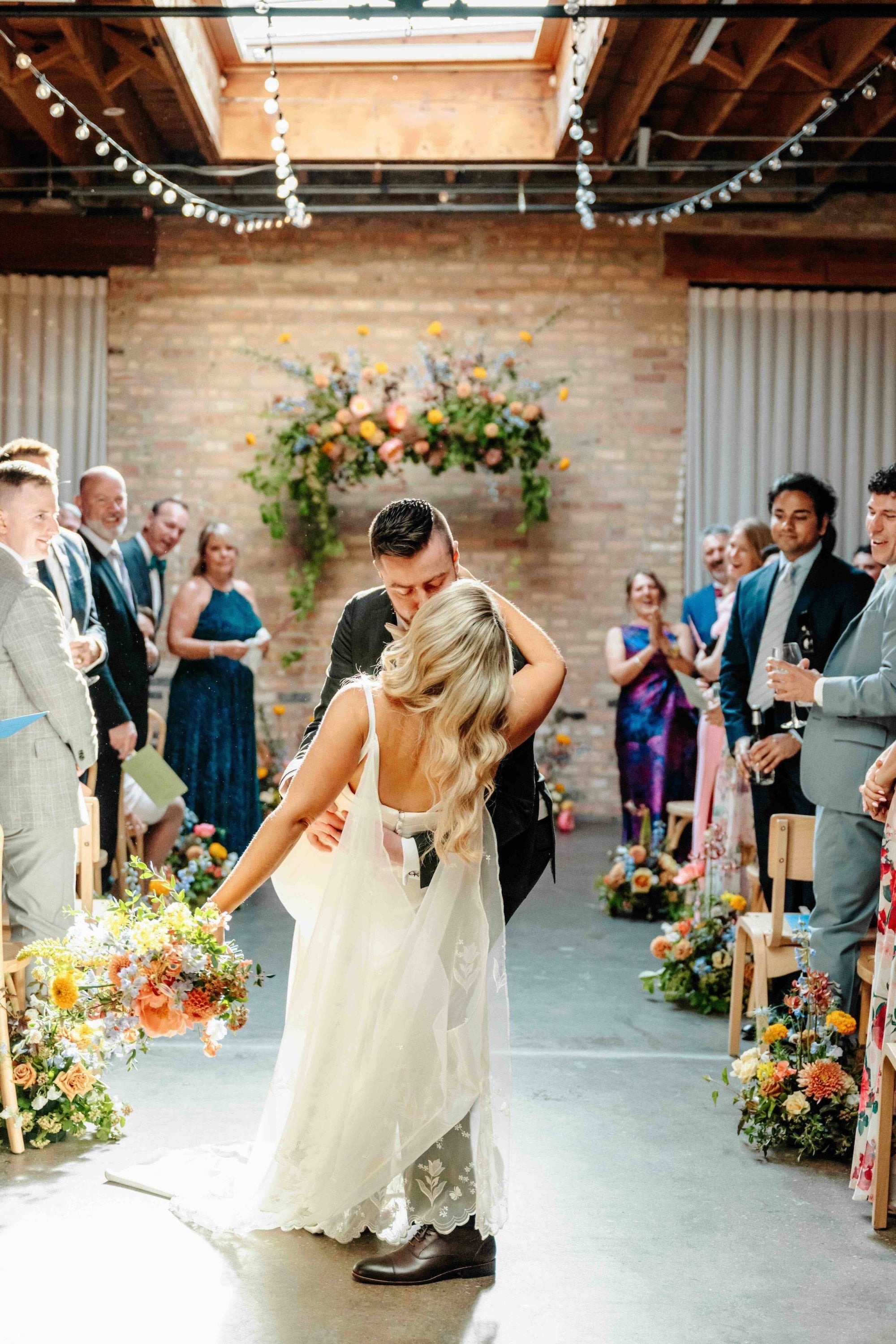 Wedding ceremony at The Arbory in Chicago with a couple walking down the aisle, surrounded by guests and floral by Sprout Home ©Joy by Jo Photography