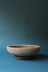 an empty Ada raw bowl and saucer by Bergs Potter on a blue backdrop.