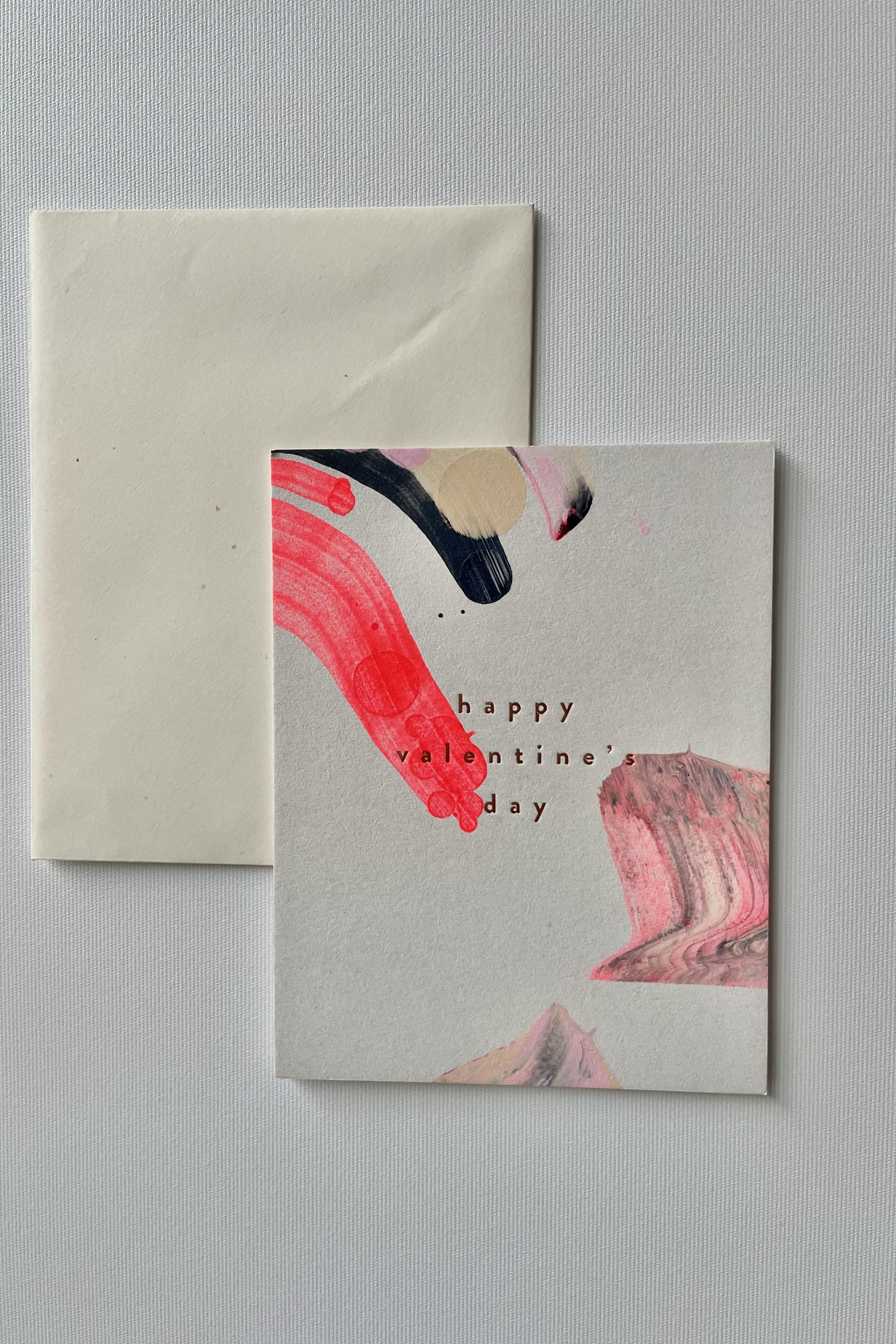 Photo of a handpainted Valentine Swirl greeting card and envelope in a white room.