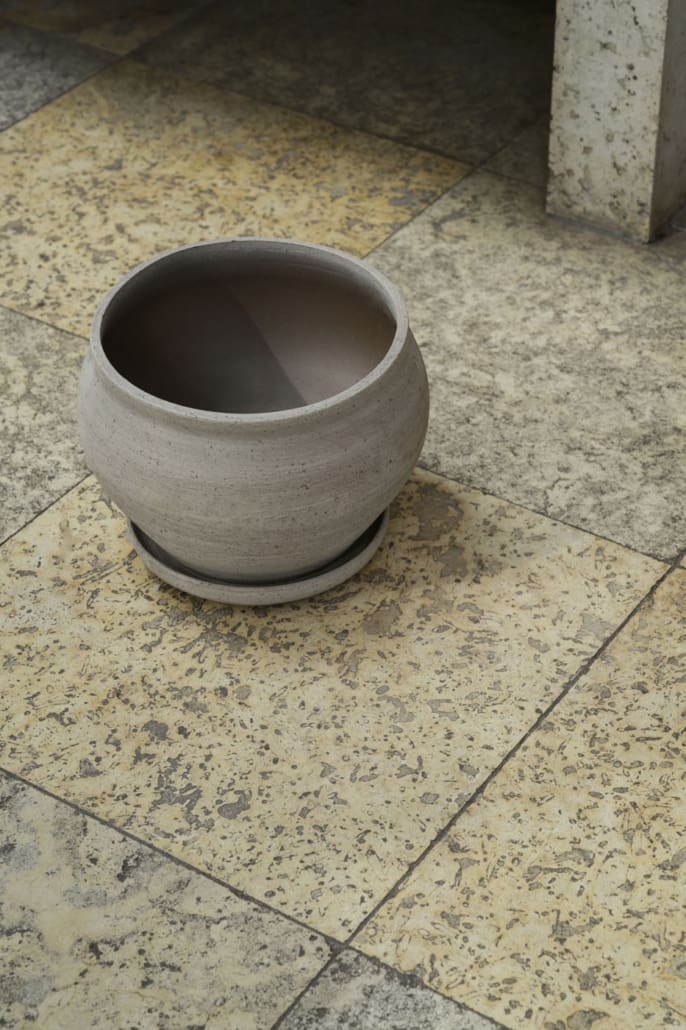 View looking down on gray clay pottery on a tiled floor
