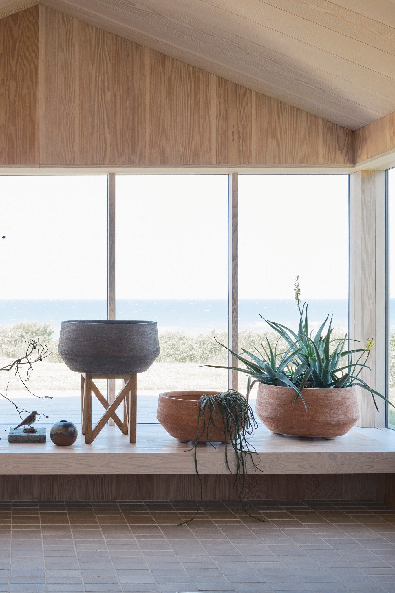 Modern interior with large windows overlooking a scenic view, featuring potted plants in Doma Pots on a ledge. ©Bergs Potter