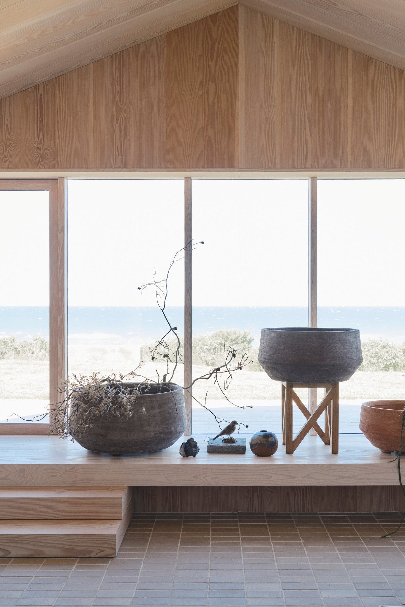 Modern interior with large windows overlooking a scenic view, featuring potted plants in Bergs Doma Grey planters on a ledge. ©Bergs Potter