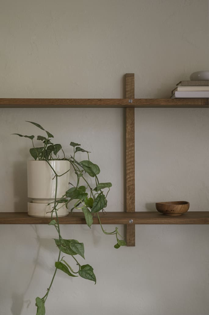 Wooden shelves with a neutral wall and a vining plant in a beige pot ©Bergs Potter