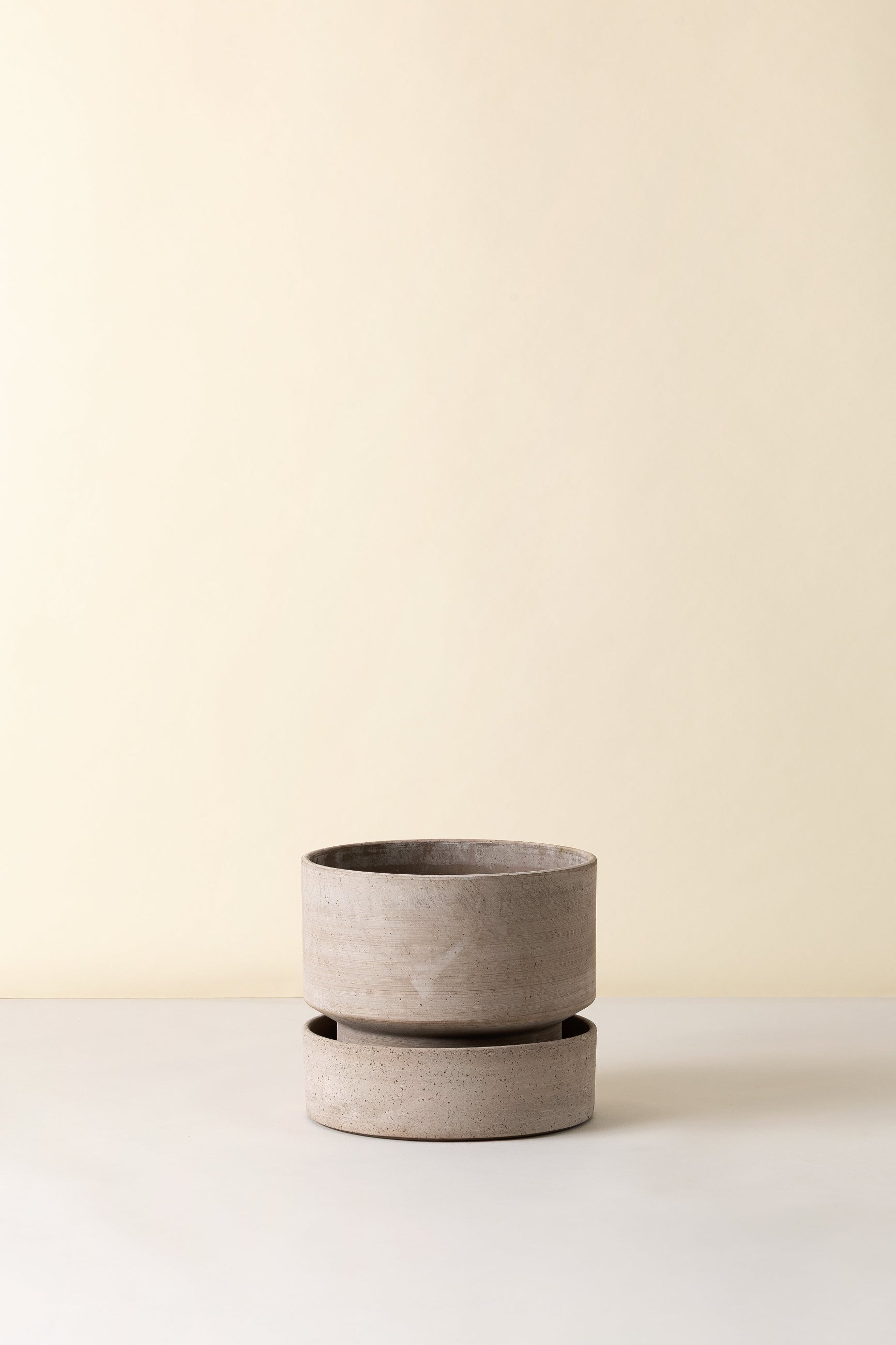 gray ceramic Hoff planters and saucer low on a light beige background ©Bergs Potter