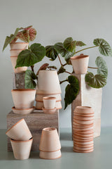 A various sized collection of Rosa Julie Berg Potter pots and saucers stacked in various groupings