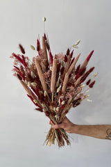 Photo of the Blind Date preserved floral arrangement with pink, mauve and berry colors preserved flowers against a white wall.