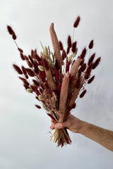 Photo of the Blind Date preserved floral arrangement with pink, mauve and berry colors preserved flowers against a white wall.