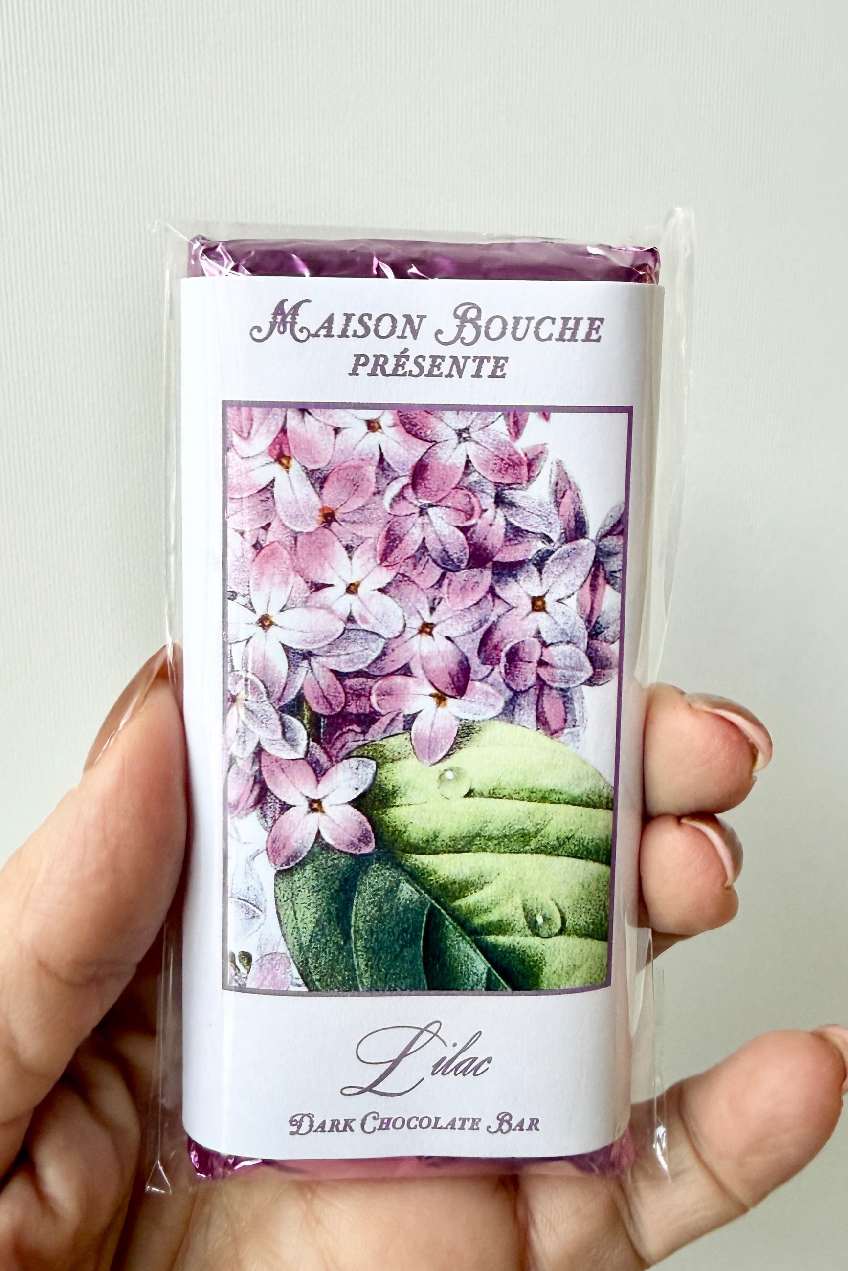 Maison Bouchee dark chocolate bar packaging with floral design held by a hand. ©Sprout Home