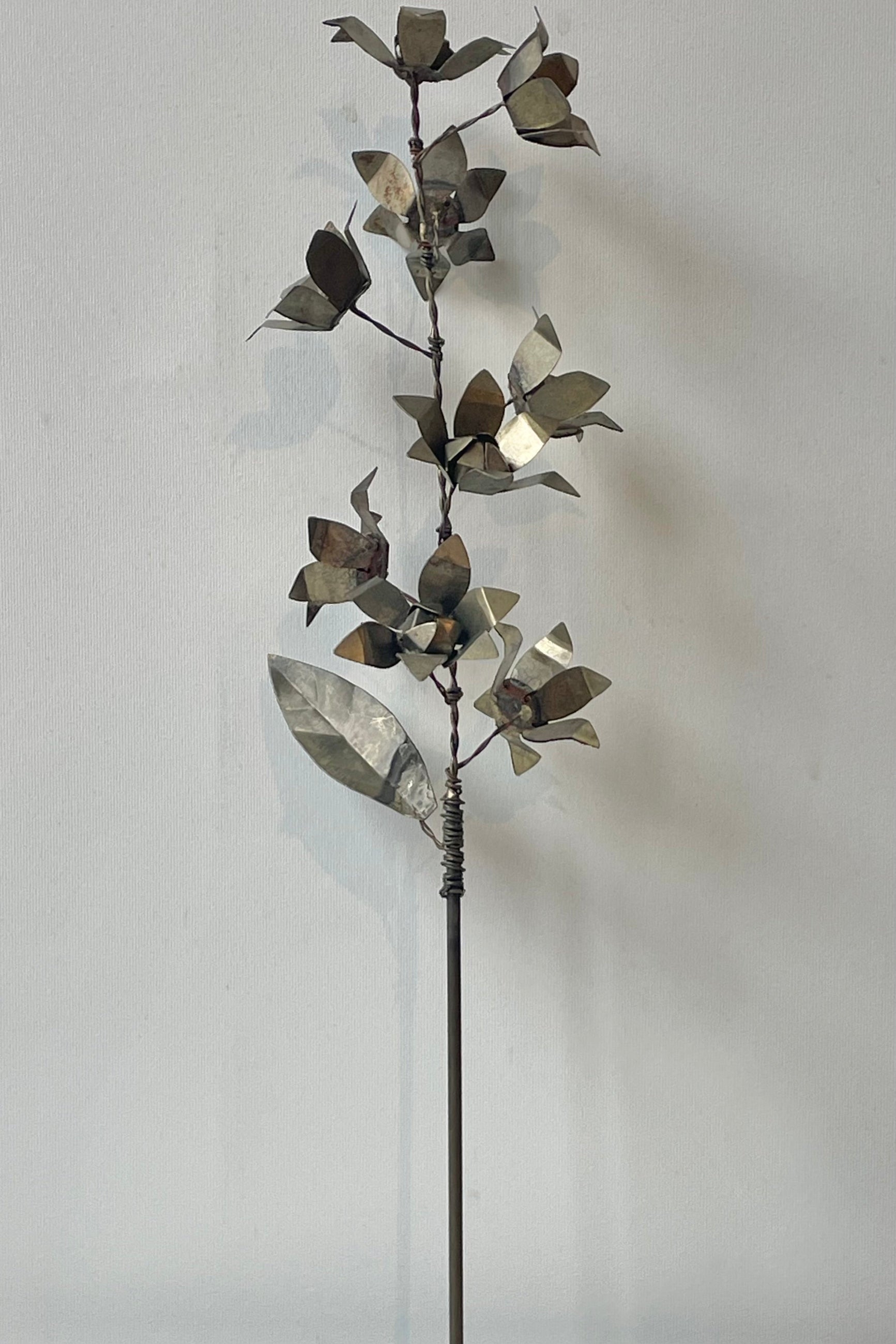 A spray of metal flowers in front of a white wall ©Sprout Home
