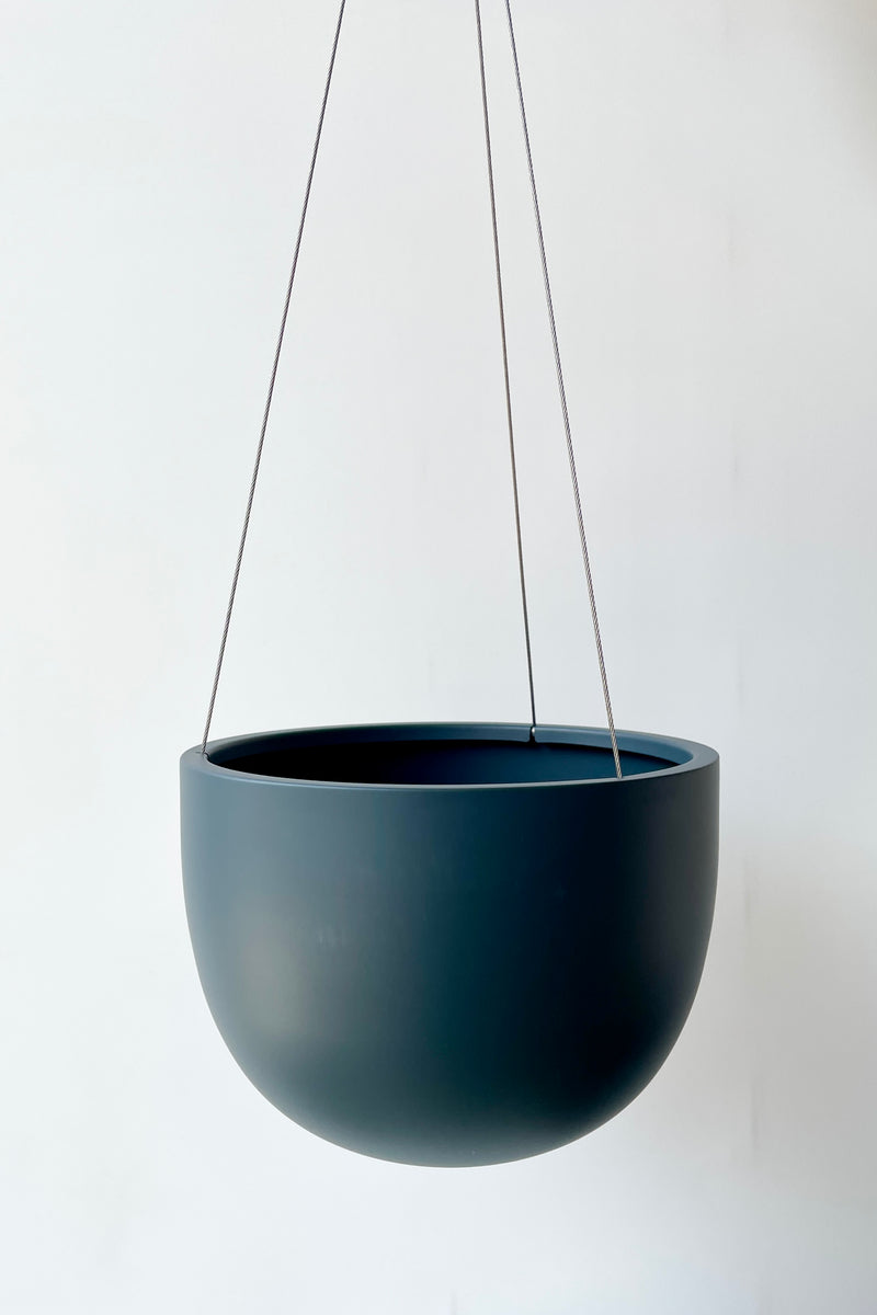 Clifton hanging pot in Matte Deep Blue empty against a white wall. 