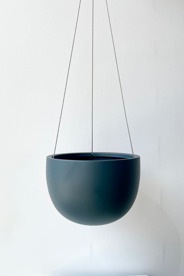 An empty Clifton Matte Deep Blue hanging pot against a white wall. 
