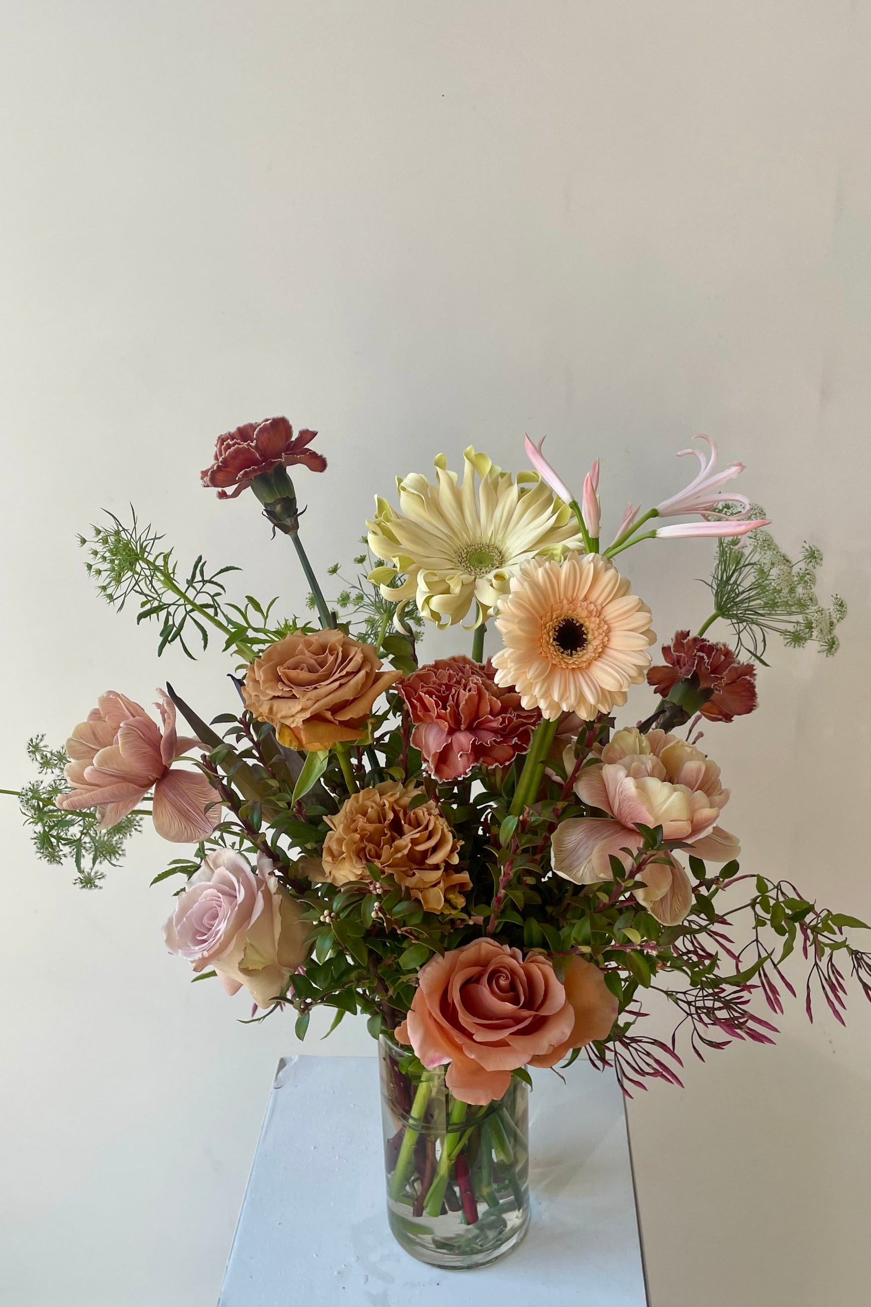 Brown and neutral flowers in a glass vase in front of a white wall ©Sprout Home #size_$130