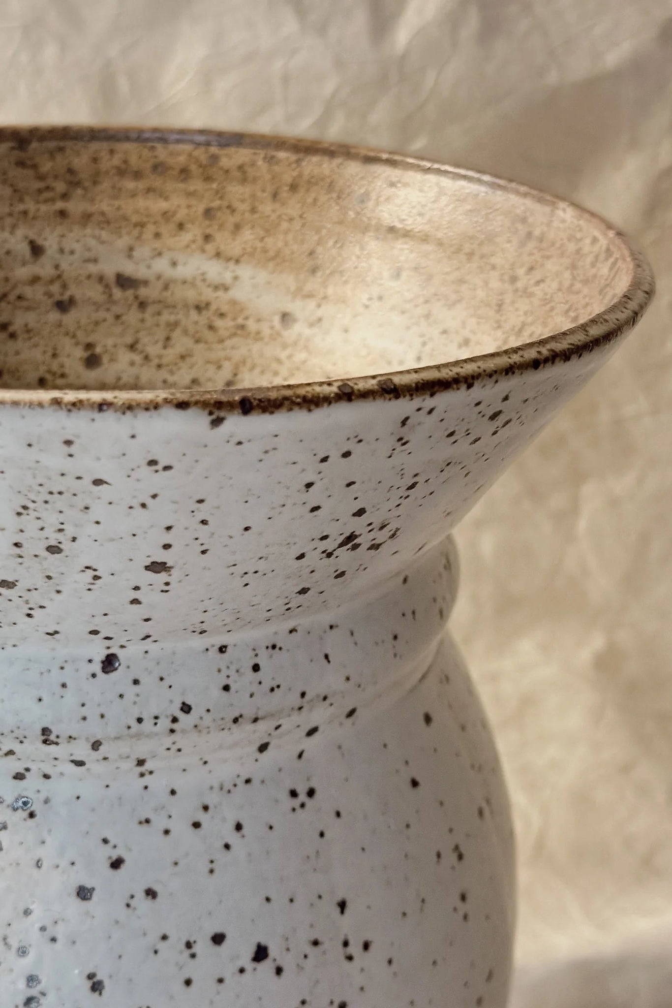 Speckled Flared Carnwall ceramic vase on a textured beige background ©Olivia Snow Ceramics