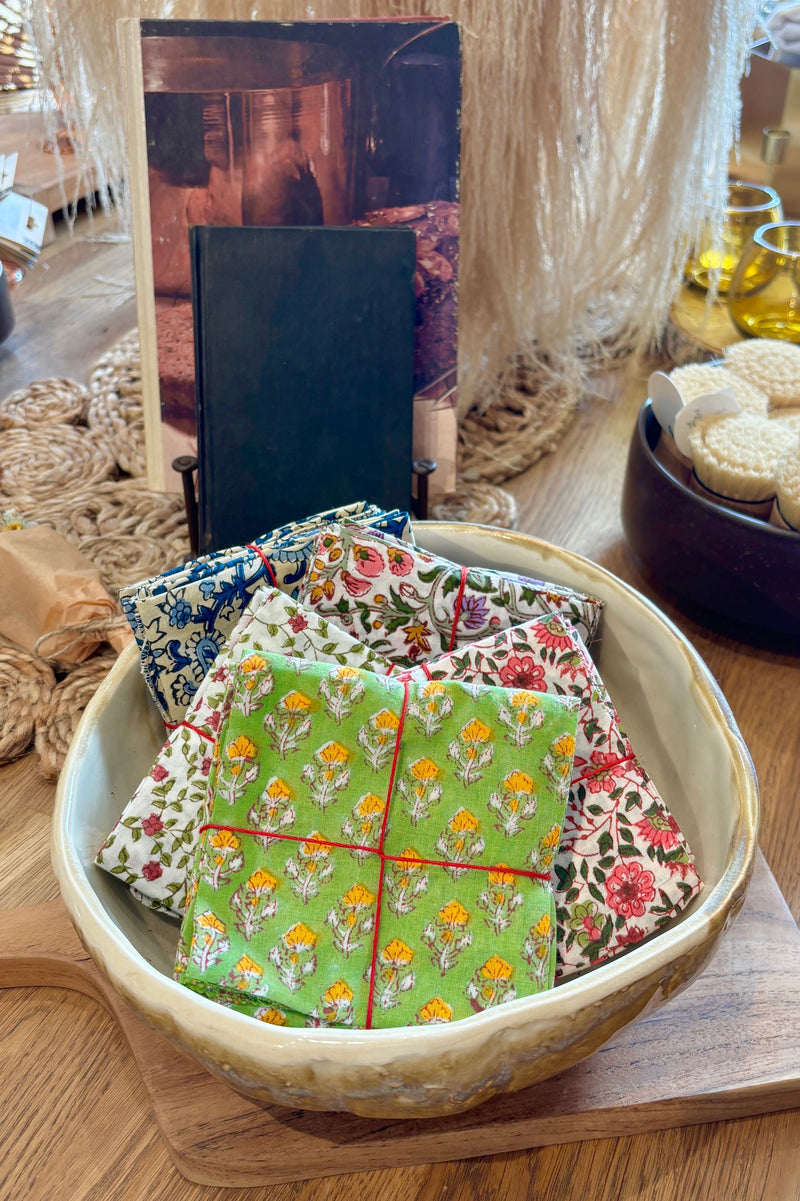 Assorted sets of hand sewn fabric napkins displayed in a ceramic bowl on a wooden table