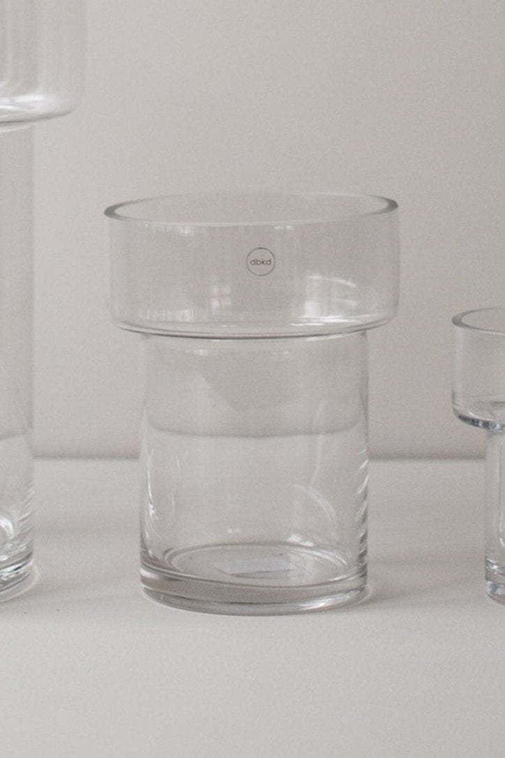 Medium size clear glass Keeper vase in an off-white setting empty and a sliver of other vases of to each side.