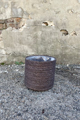 Photo of black seagrass basket with liner against a cement wall.