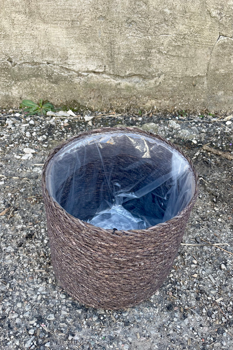 Photo from above of black seagrass basket with liner against a cement wall.