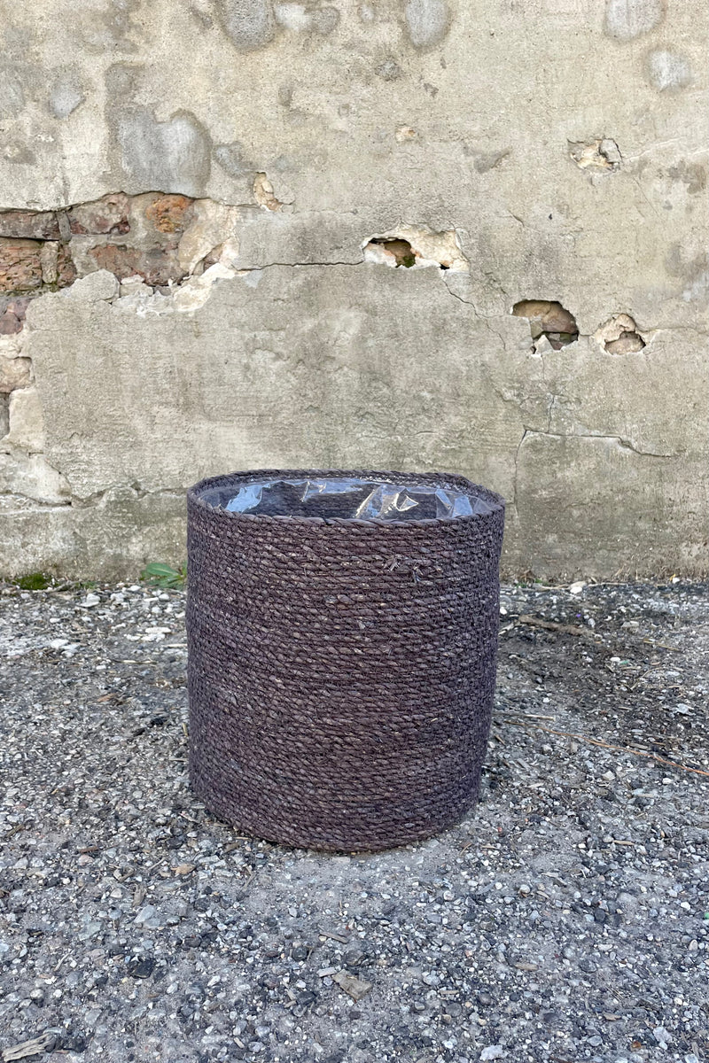 Photo of black seagrass basket with liner against a cement wall.