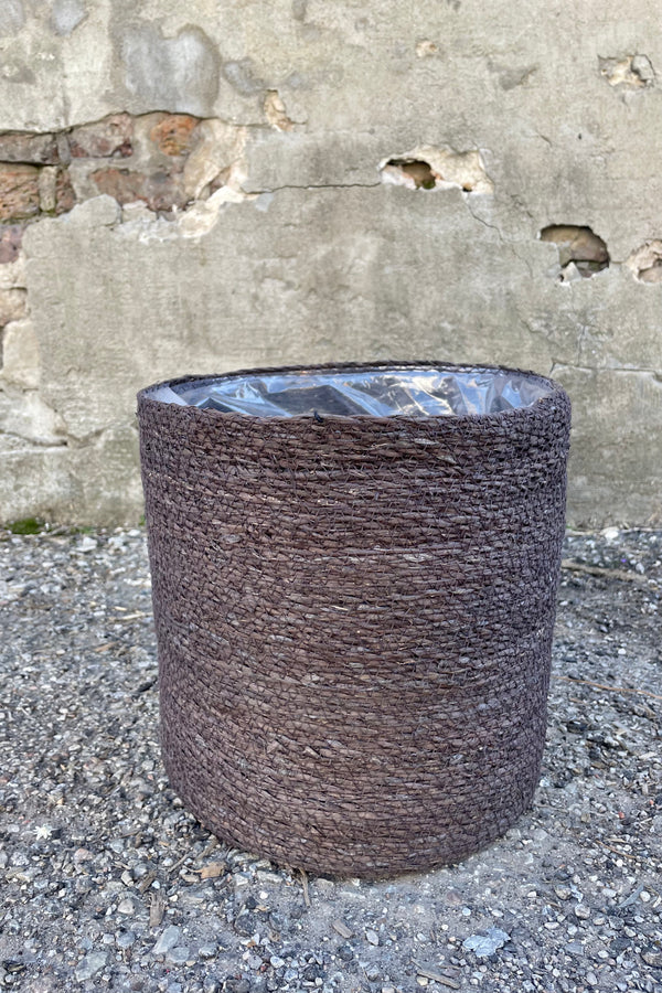 Photo of black seagrass basket with liner against a cement wall.