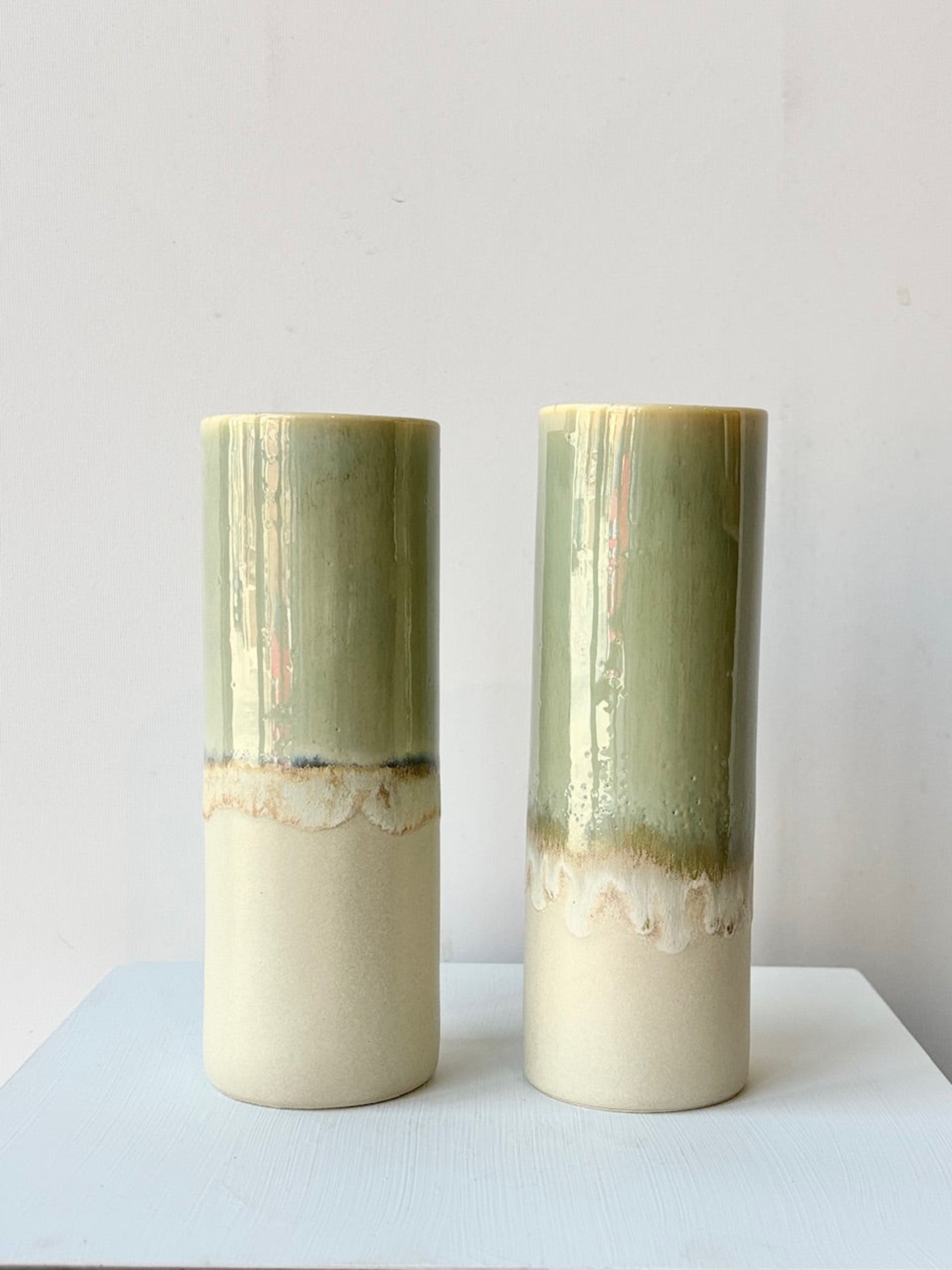 Two cylindrical ceramic vases with gradient green and beige colors on a light gray background ©Sprout Home