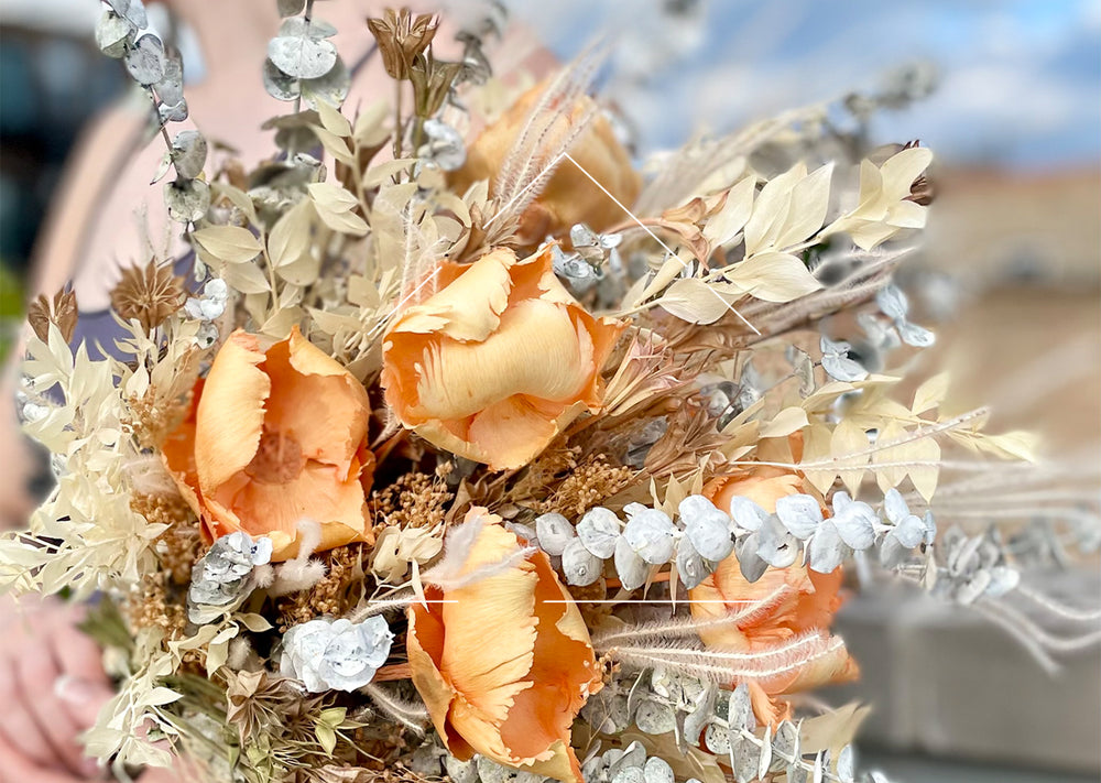 woman holding a bouquet of peach and cream colored dried flowers