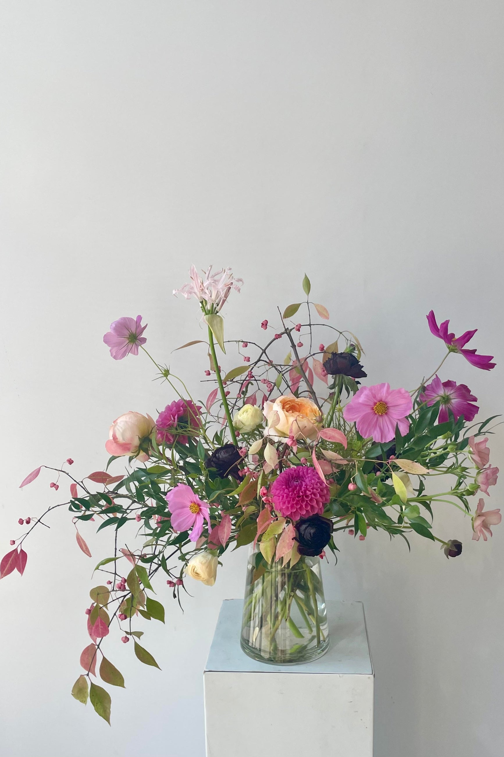 An example of fresh Floral Arrangement Dusk by Sprout Home Floral in Chicago Cosmos and other flowers in glass against a white wall #size_$160