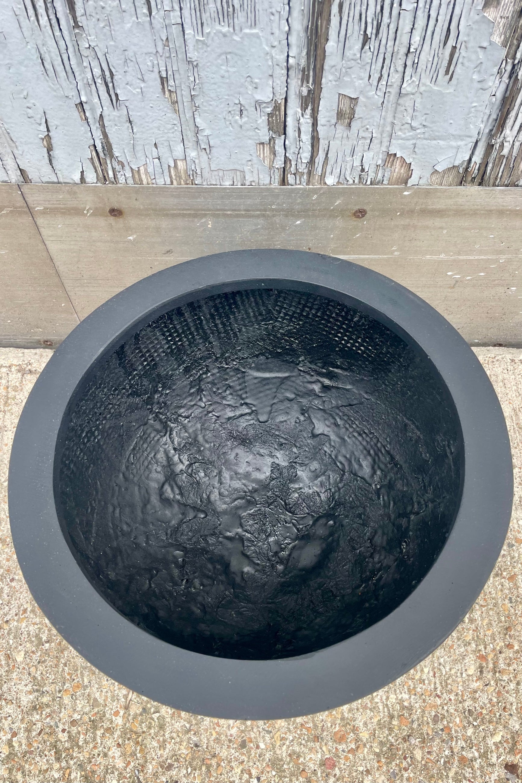 A bowl shaped black planter shown from above in front of a wooden wall ©Sprout Home